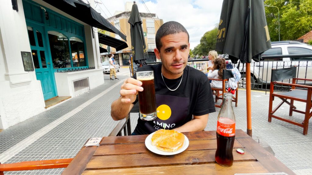Edu comiendo en Córdoba con un Fernet en la mano, bebida típica cordobesa