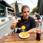 Edu comiendo en Córdoba con un Fernet en la mano, bebida típica cordobesa
